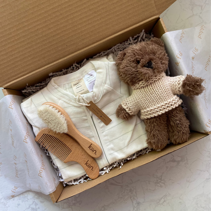 Baby gift set with teddy bear, clothing, and toys in a gift box